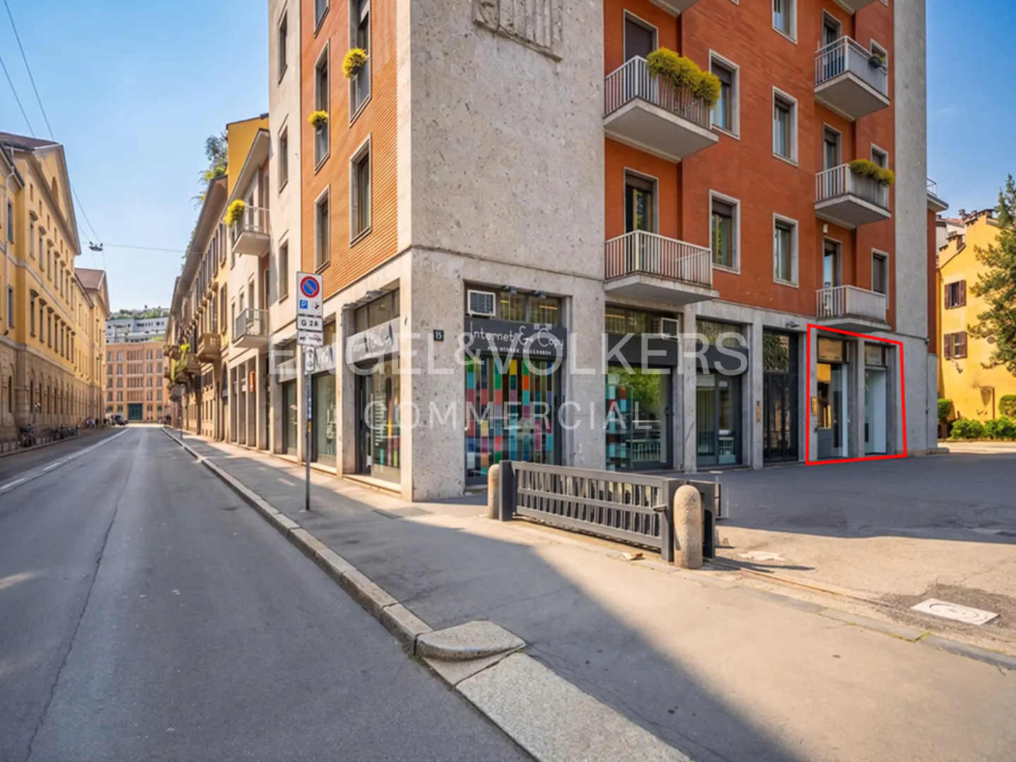 Street view of an Engel & Volkers Commercial office in a multi-story building with balconies and a red outline around a storefront.