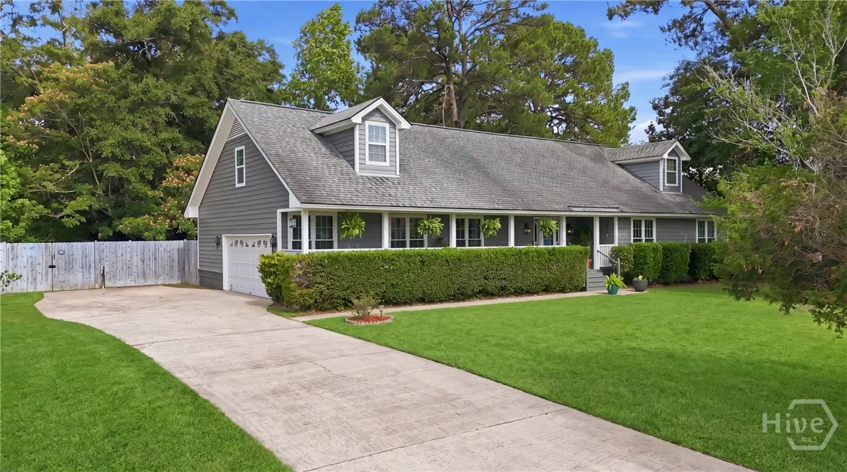 Gray house with a gray roof, white trim, and a green lawn. A green hedge runs along the front of the house.