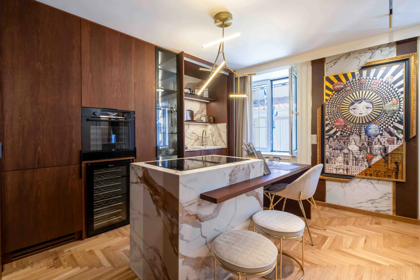 Modern kitchen with dark wood cabinets, a marble island with a cooktop, two stools, and a large, vibrant wall art piece.