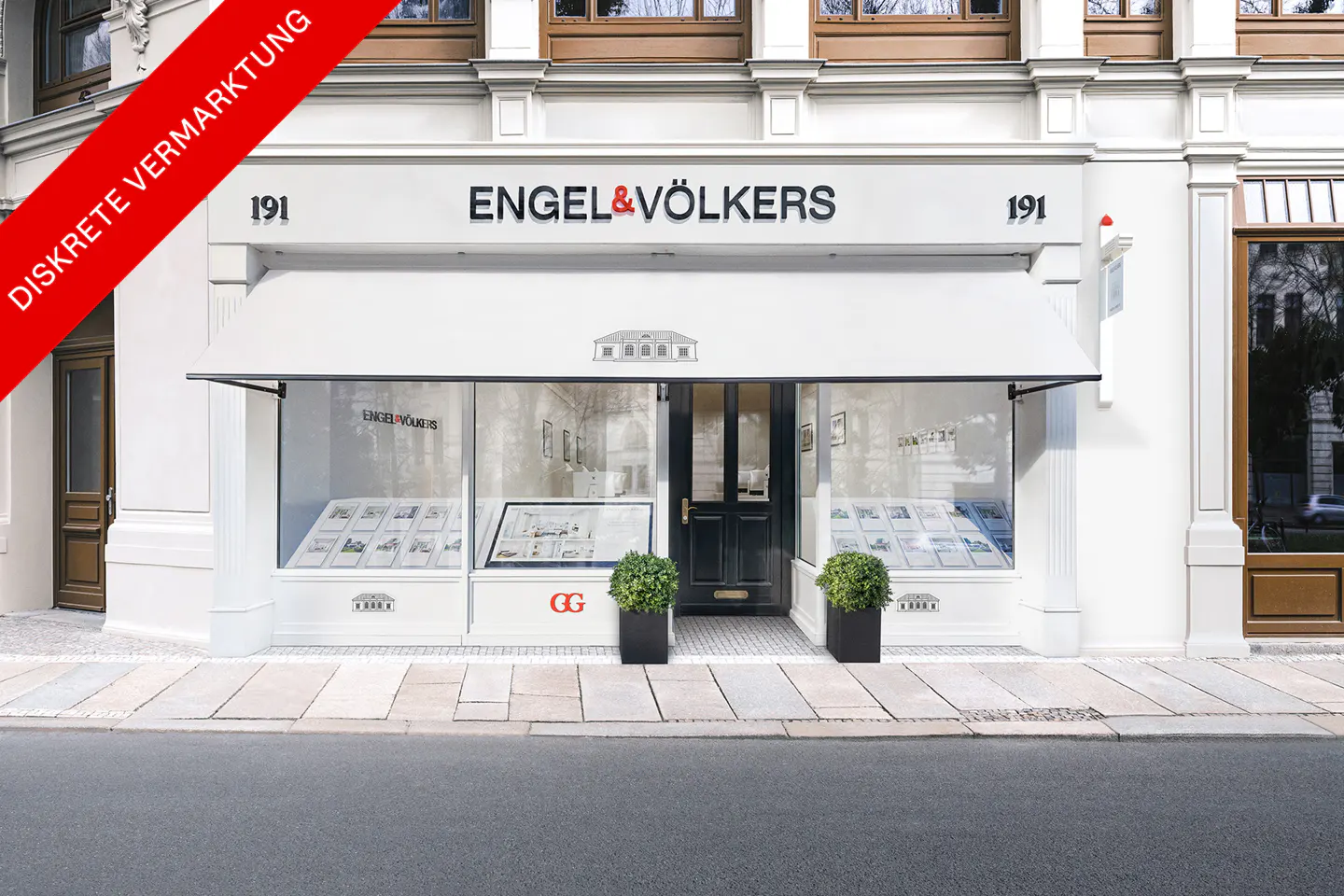 Exterior of Engel & Völkers real estate office with white awning, black door, and window displays. "191" above the entrance.