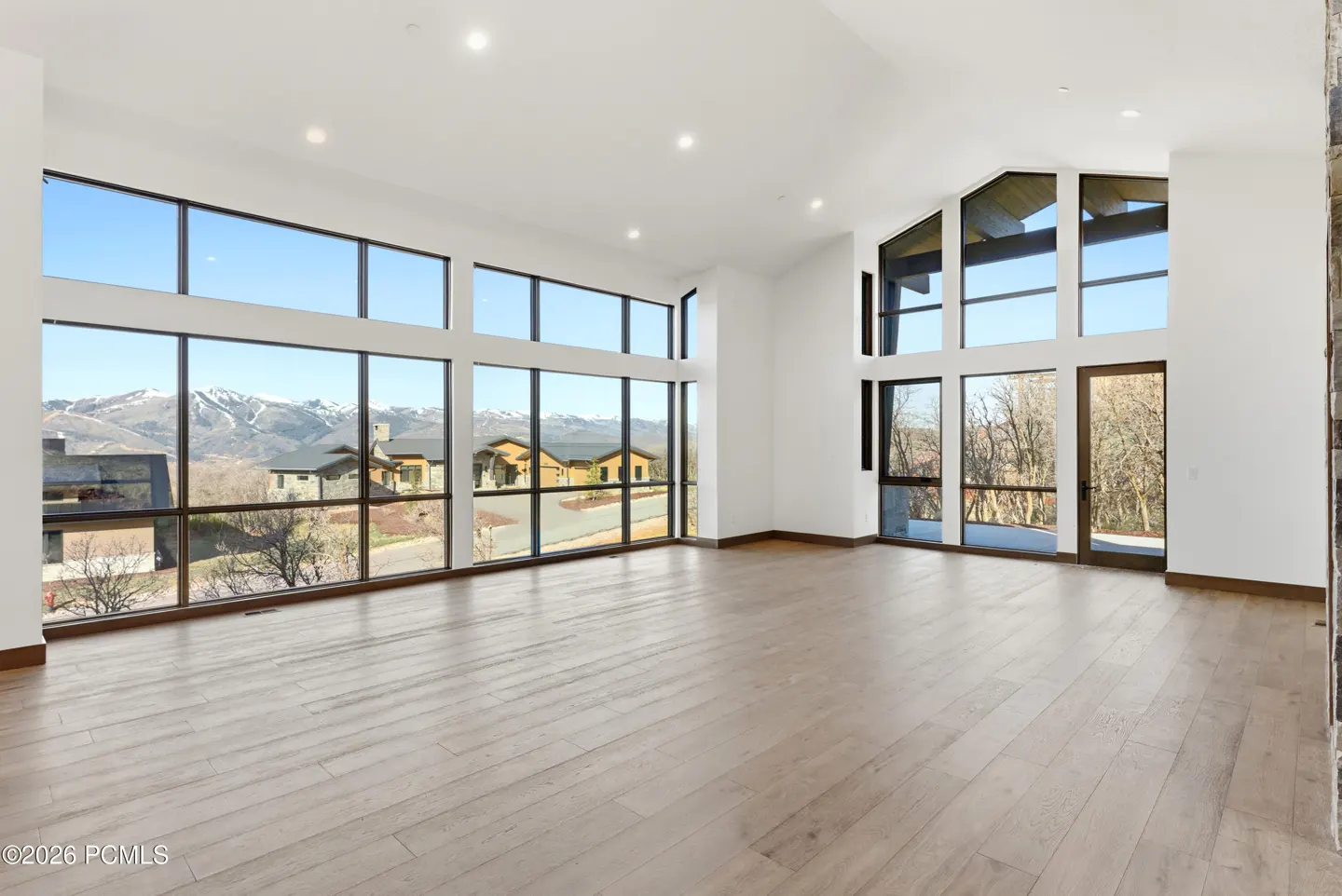 Bright, empty living room with hardwood floors and large windows showing mountain views.