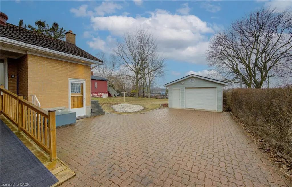 Exterior view of a yellow brick house with a detached garage and a brick driveway.