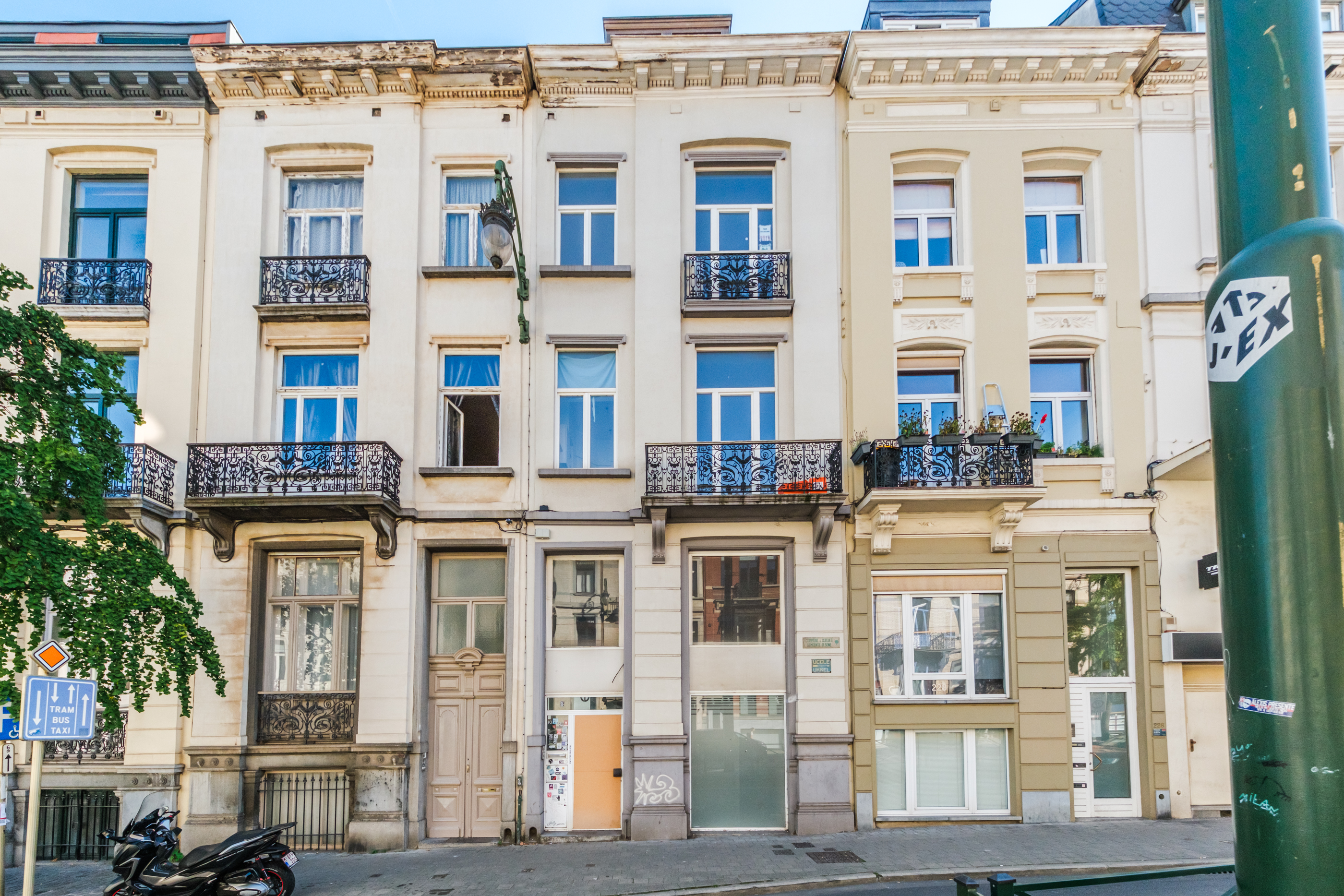 Row of historic European townhouses with ornate iron balconies, large windows, and a mix of cream and beige facades. [AI-generated text]