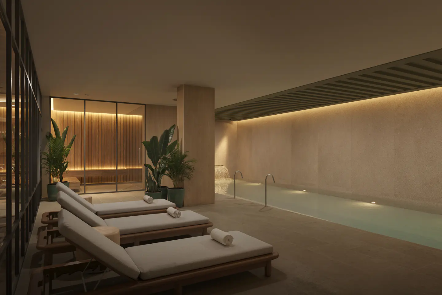 Luxury indoor spa with three lounge chairs, potted plants, and a softly lit swimming pool with a small waterfall feature.