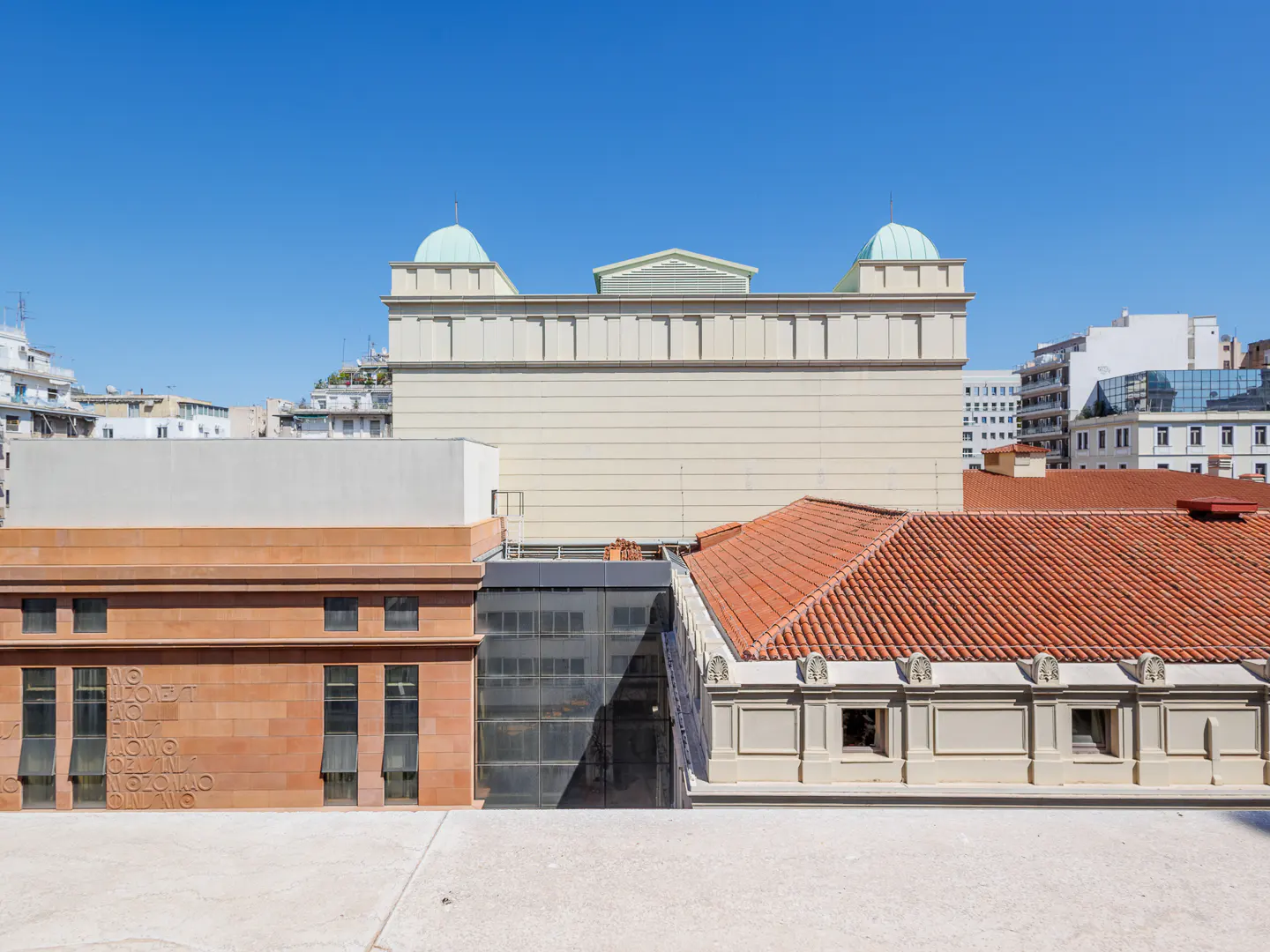 Cityscape view of various buildings with different architectural styles under a clear blue sky.