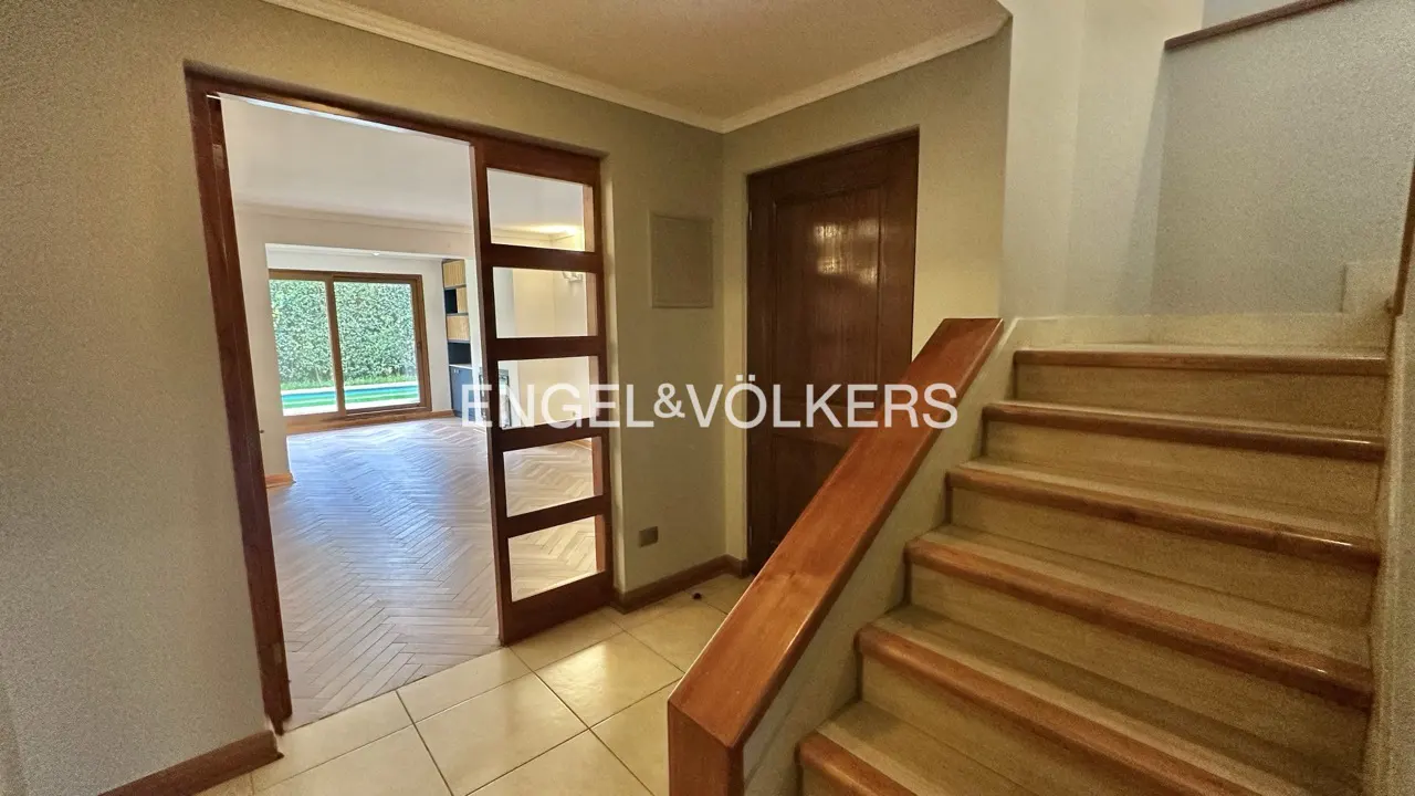 Foyer view with wooden stairs, a door, and a glass-paneled sliding door leading to a room with a pool view.