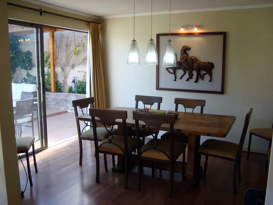 Dining room with wood table, chairs, and hardwood floors. Sliding glass doors lead to a patio. A horse art piece hangs on the wall.
