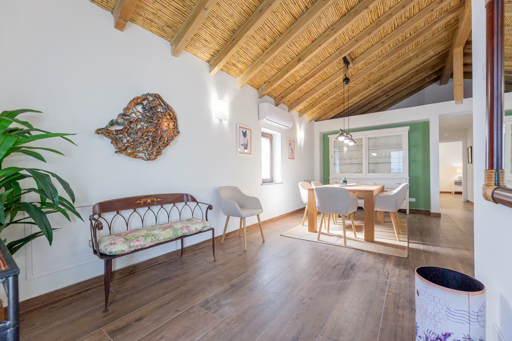 Interior view of a dining room with a bench, chairs, table, and straw ceiling.