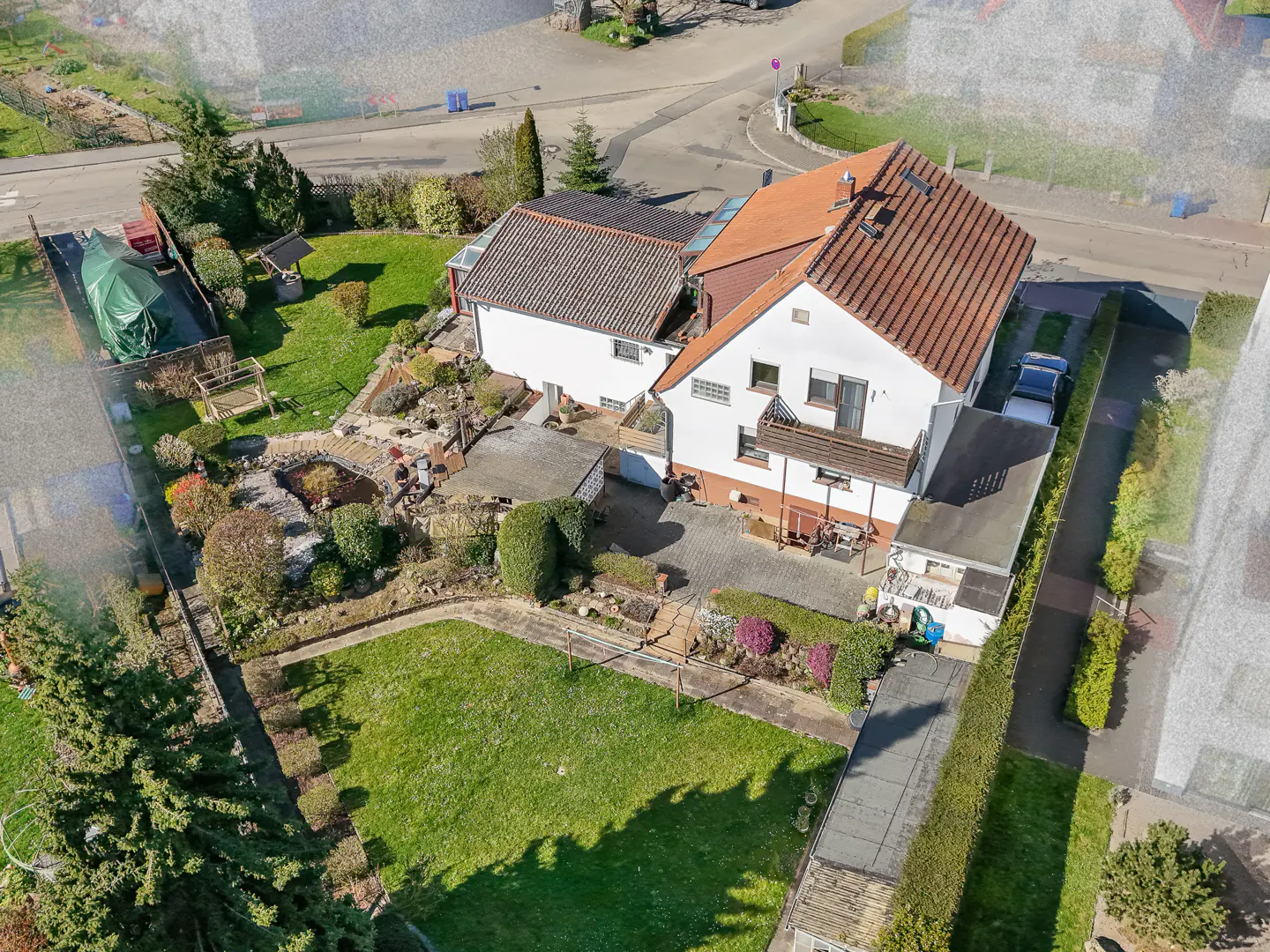 Aerial view of a white two-story house with a red tile roof and a large green lawn.