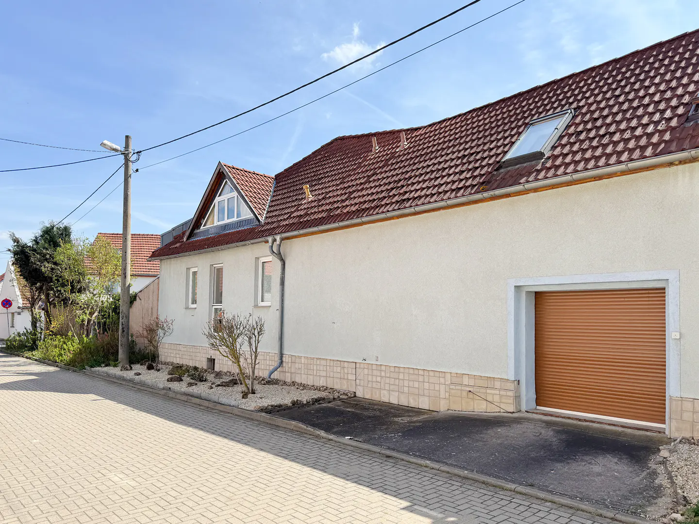 A one-story house with a red tile roof and a brown garage door on a sunny day.
