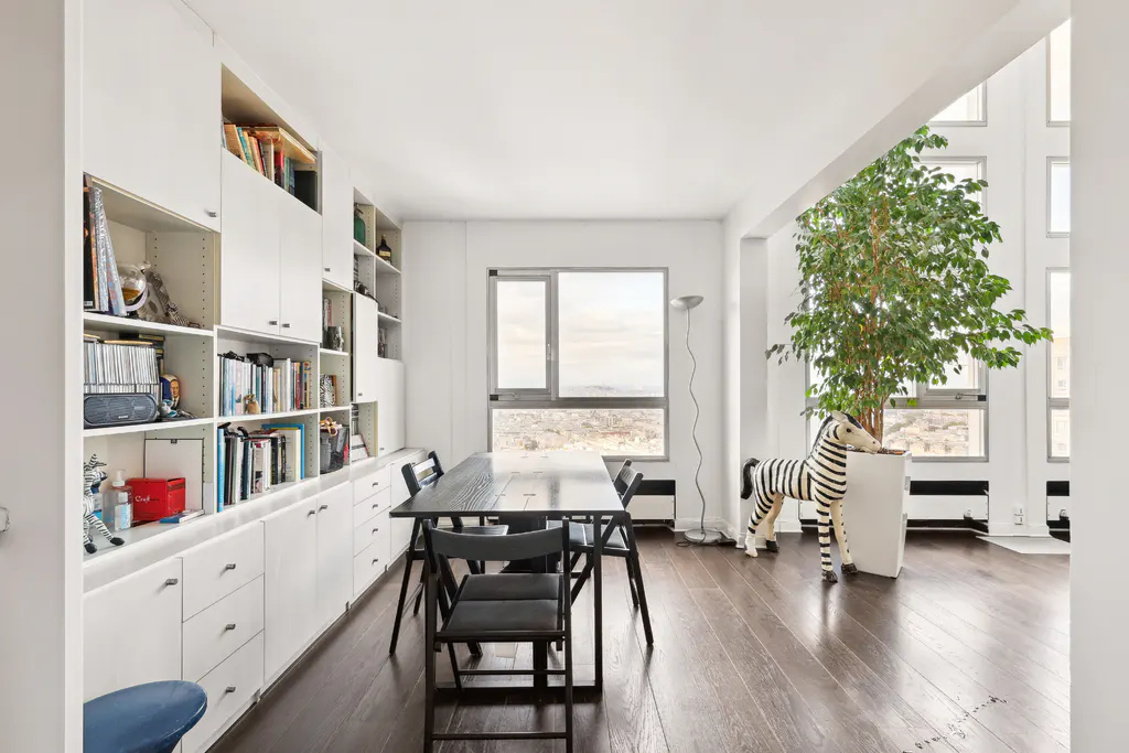 Bright, modern room with dark wood floors, white built-in shelves, a black table with chairs, and a zebra statue near a large window.