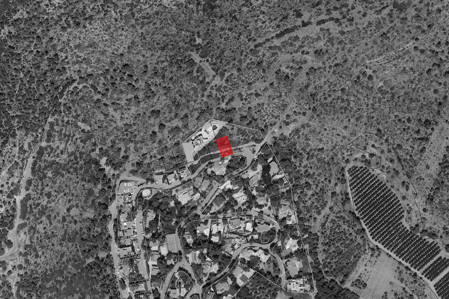 Aerial view of a residential neighborhood with a red rectangle highlighting a specific plot of land for sale.