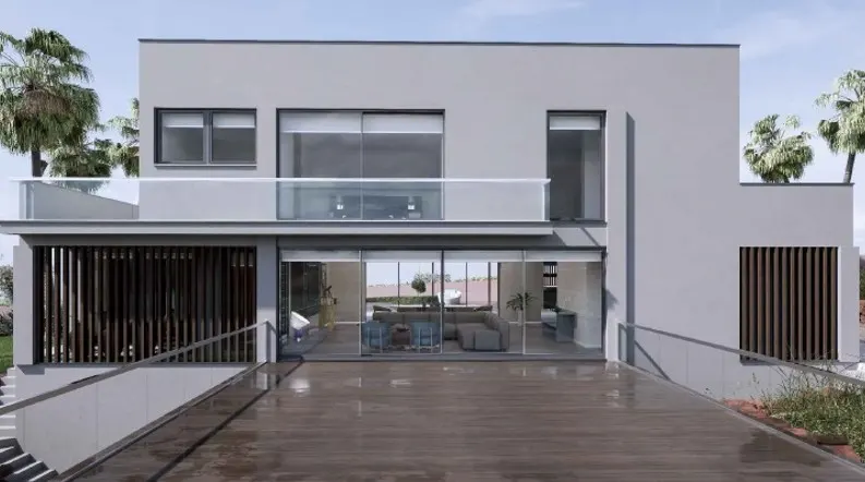 Modern gray two-story house with a wood deck, glass railings, and palm trees in the background.