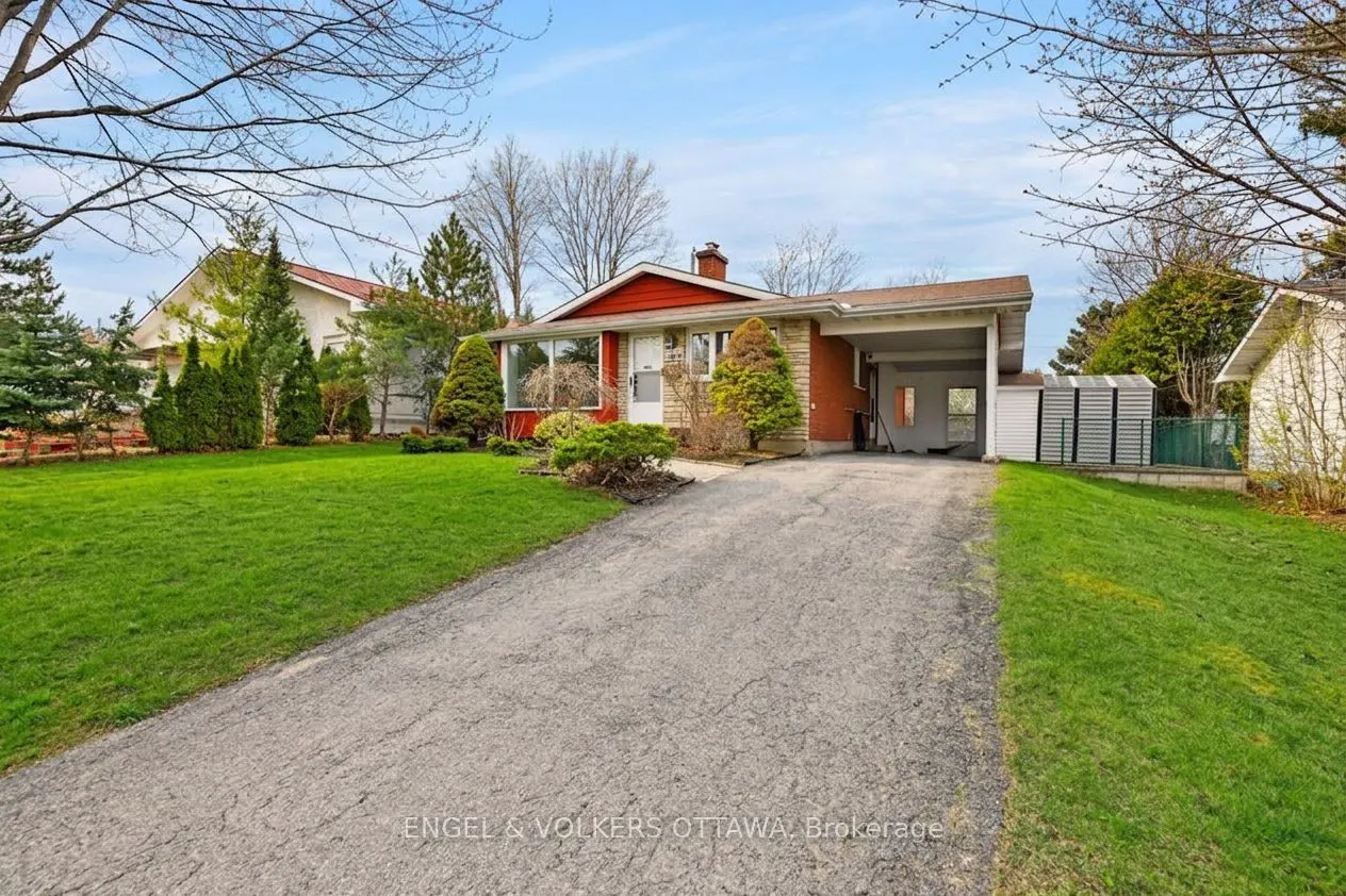 A single-story home with red trim, a carport, and a long driveway on a sunny day.