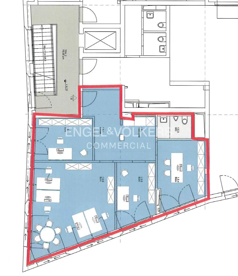Floor plan of a commercial space with desks, chairs, bathrooms, and a staircase, highlighted in blue with a red border.
