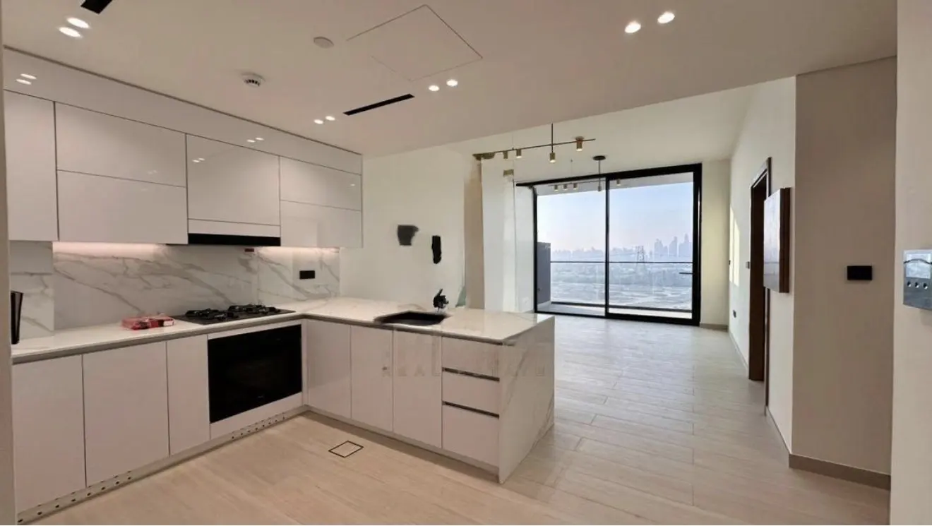 A modern, bright kitchen with white cabinets, marble countertops, and a black oven. A large window offers a city view.