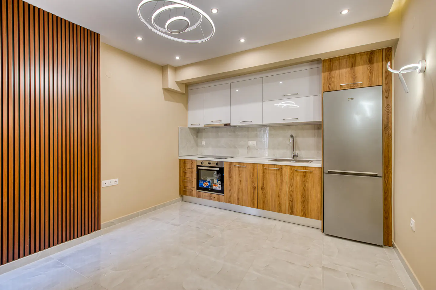A modern kitchen with wood and white cabinets, stainless steel appliances, and a unique wood slat wall.