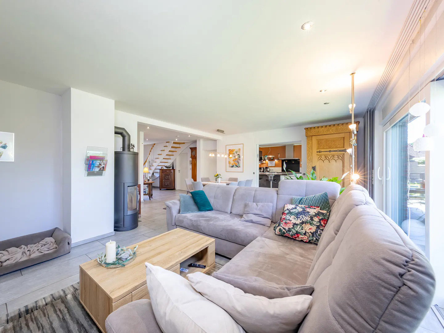 Spacious living room with a grey sectional sofa, wooden coffee table, black fireplace, and view into the dining area.