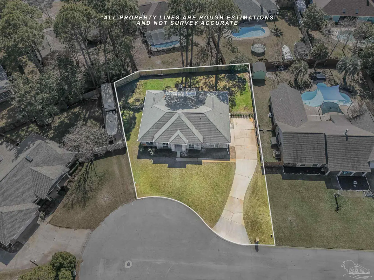 Aerial view of a single-story house with a gray roof, surrounded by green lawn and trees, property lines are outlined in white.