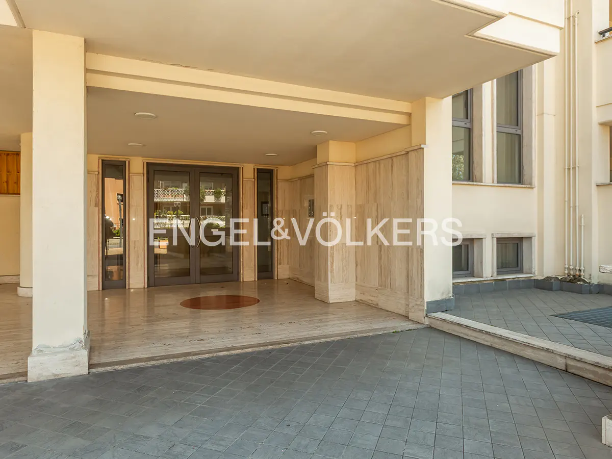 Exterior view of a building entrance with marble columns and an Engel & Völkers logo.