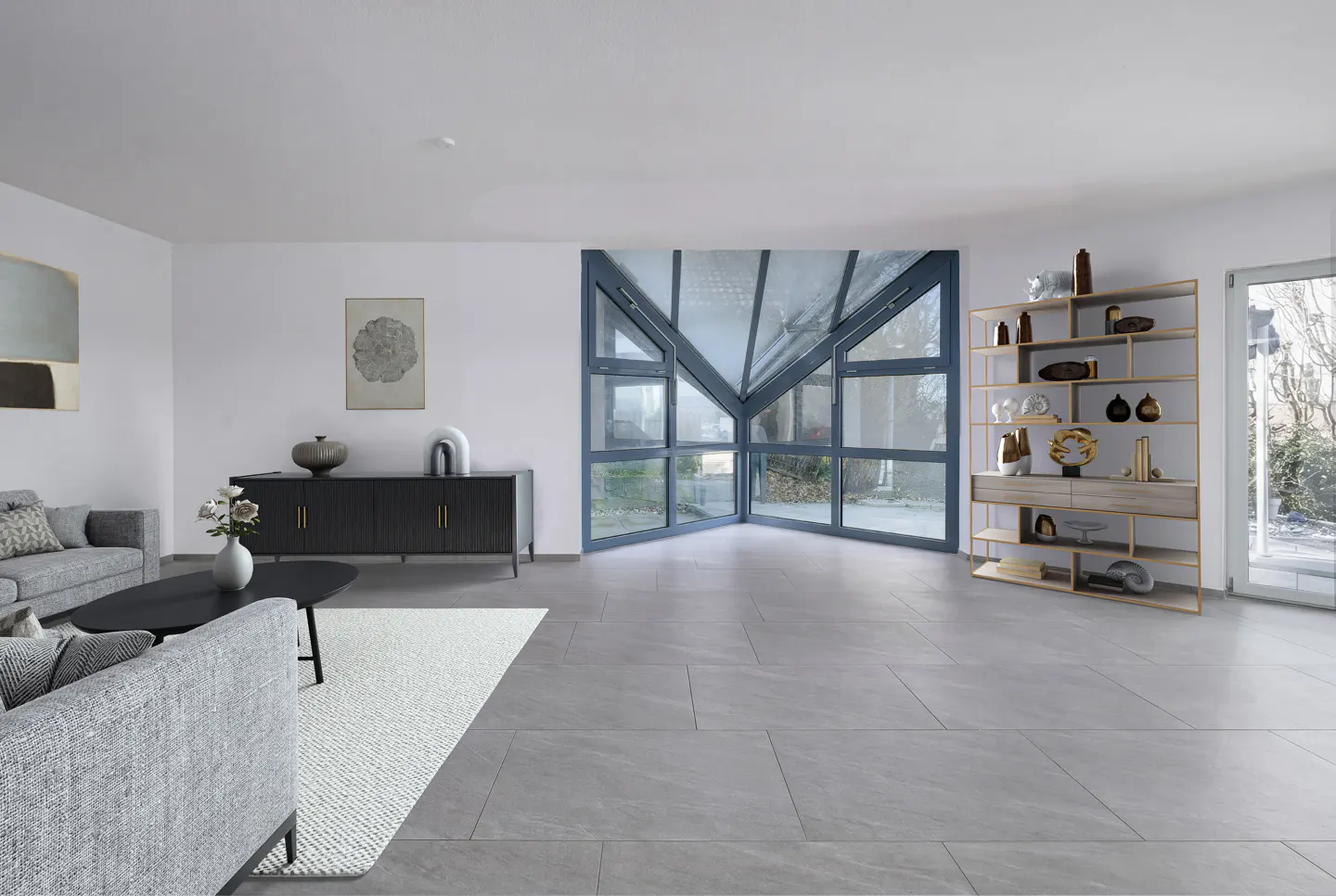 Bright living room with gray tile floor, gray sofa, black cabinet, and a unique window design. A bookshelf stands near a sliding glass door.