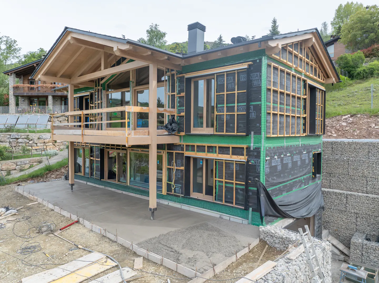 A modern house under construction with a wood frame and a concrete patio.