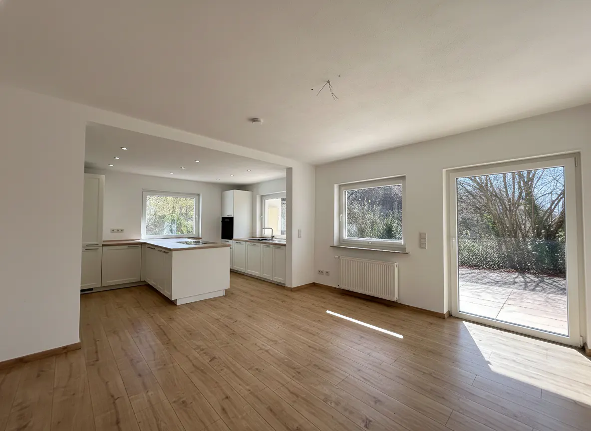 Bright, open-concept kitchen and living room with wood floors, white walls, and cabinets. Large windows and sliding glass door to the outside.