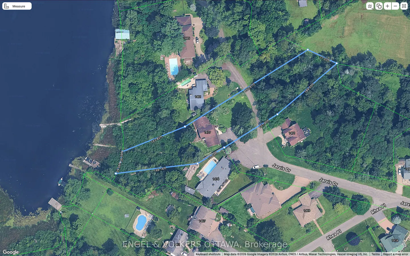 Aerial view of a wooded property outlined in blue, bordering a lake with docks and several houses with pools nearby.