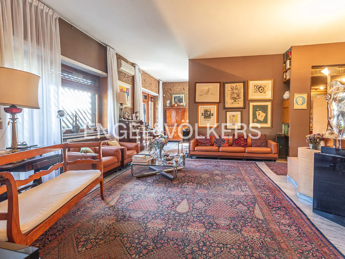 A living room with brown walls, a patterned rug, and orange leather furniture. Art hangs on the walls.