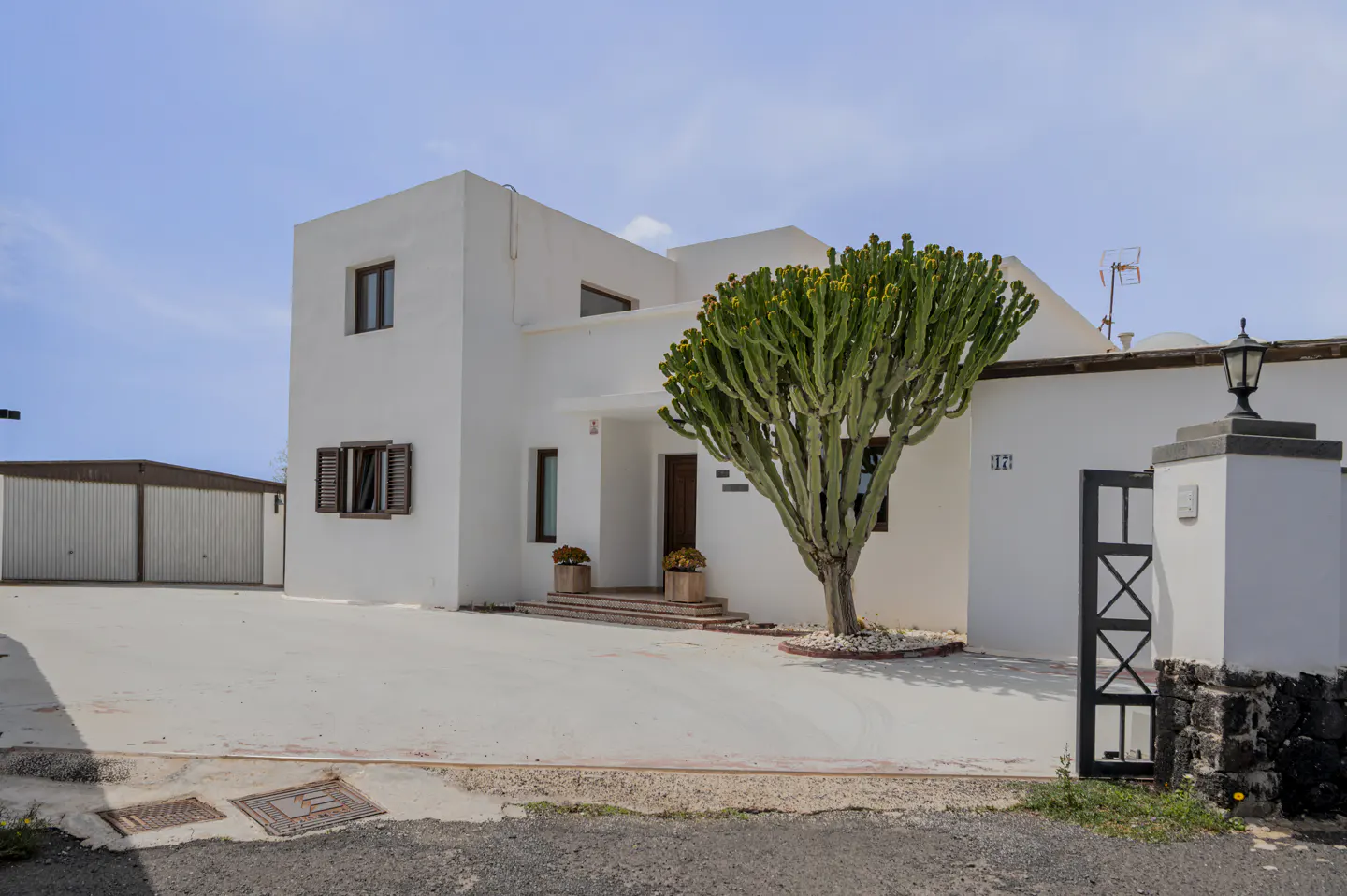 Exterior of a two-story white house with brown shutters and a large cactus in the front yard.