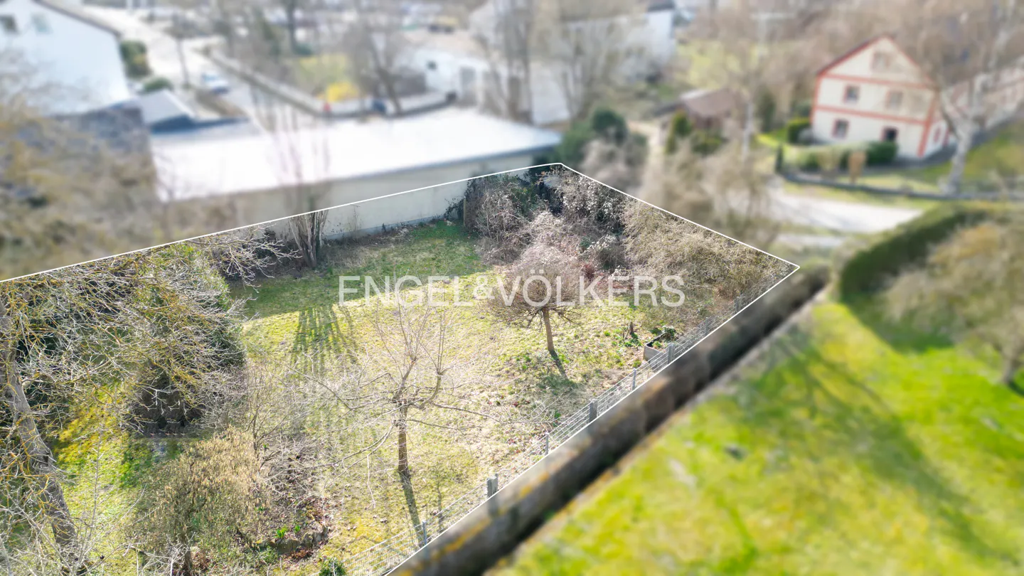 Aerial view of a vacant lot with a white border, green grass, trees, and the Engel & Völkers logo.