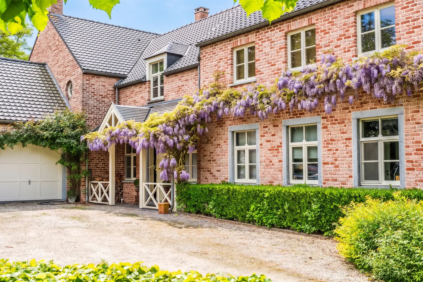 Exterior of a two-story brick house with white trim and purple wisteria vines.