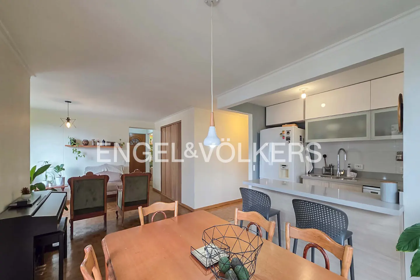 Open-concept living space with a dining table, piano, and kitchen with white cabinets and a breakfast bar.