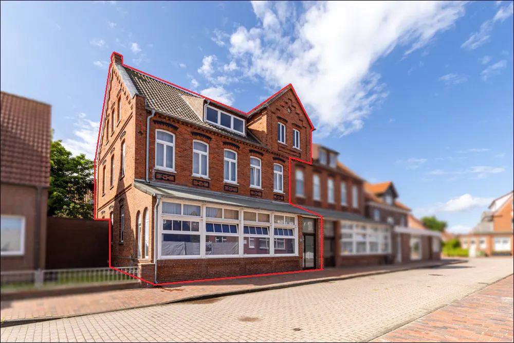 A three-story brick building with white-framed windows under a blue sky with clouds.