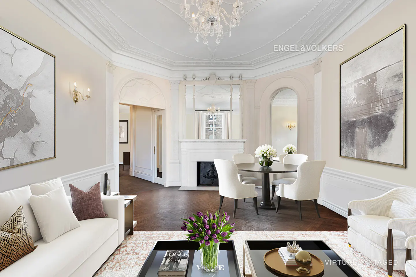 Elegant living room with white sofas, abstract art, and a dining area with a fireplace. A crystal chandelier hangs from the ornate ceiling.