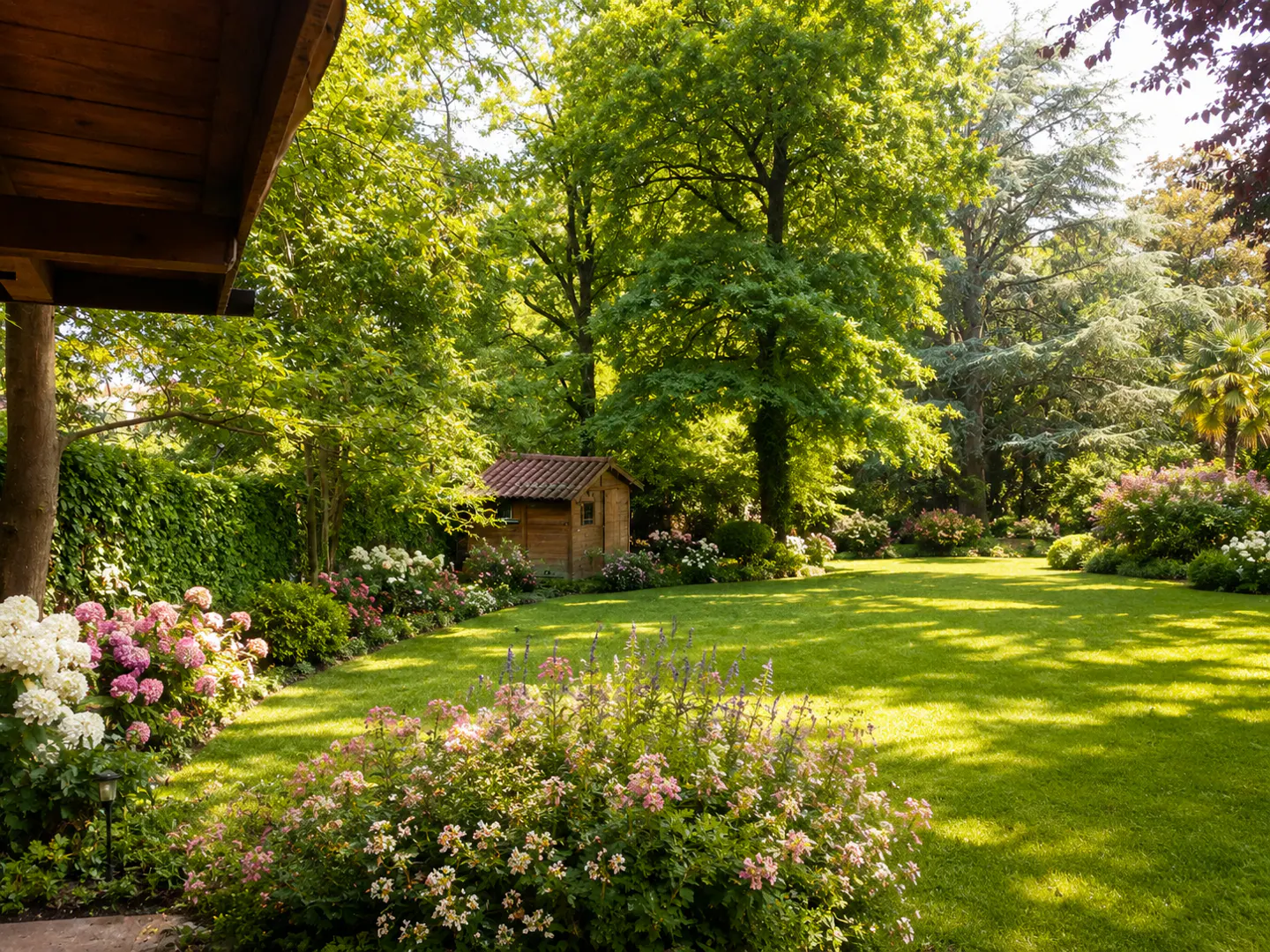 Lush green lawn with flowerbeds and trees. A small wooden shed sits in the background. Part of a wooden structure is visible on the left.