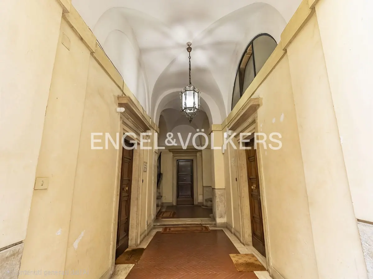 Hallway with arched ceiling, cream walls, and brown tile floor. A lantern hangs from the ceiling. Two brown doors are on either side of the hallway.