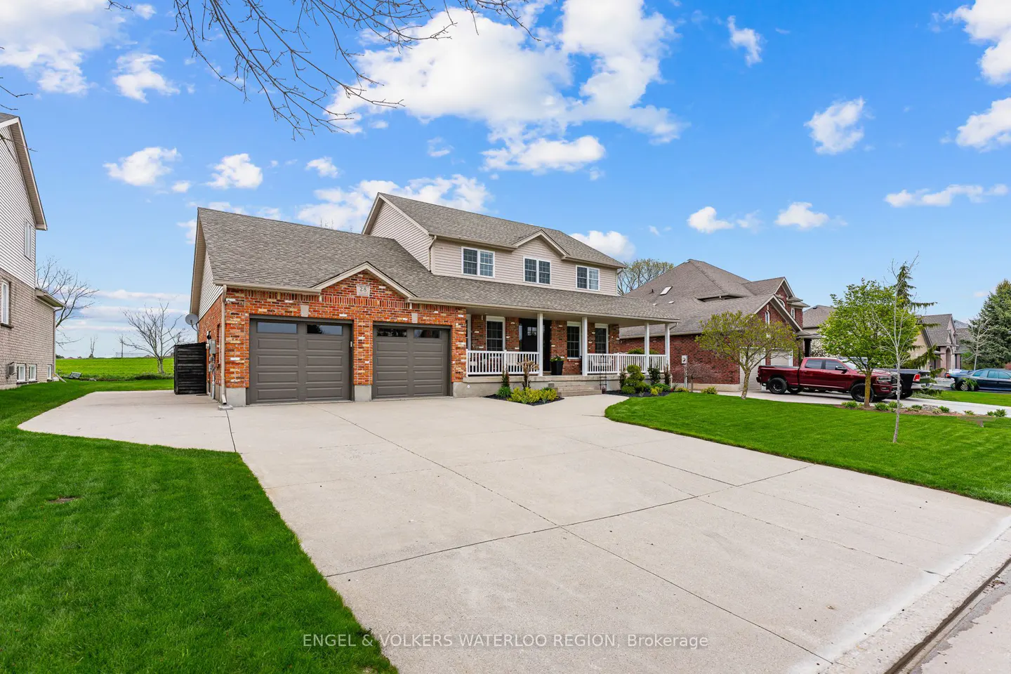 Two-story house with brick and siding, a front porch, a double garage, and a long driveway.