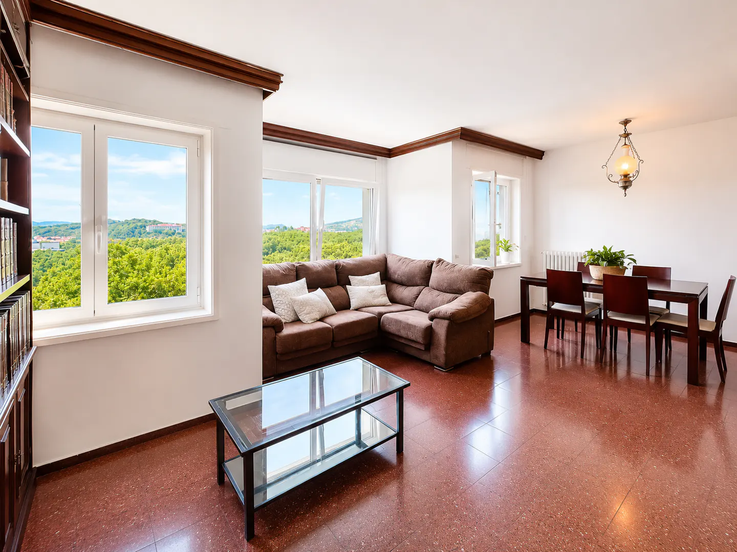 Bright living and dining room with brown sectional sofa, glass coffee table, and dining set on reddish-brown tile floors.