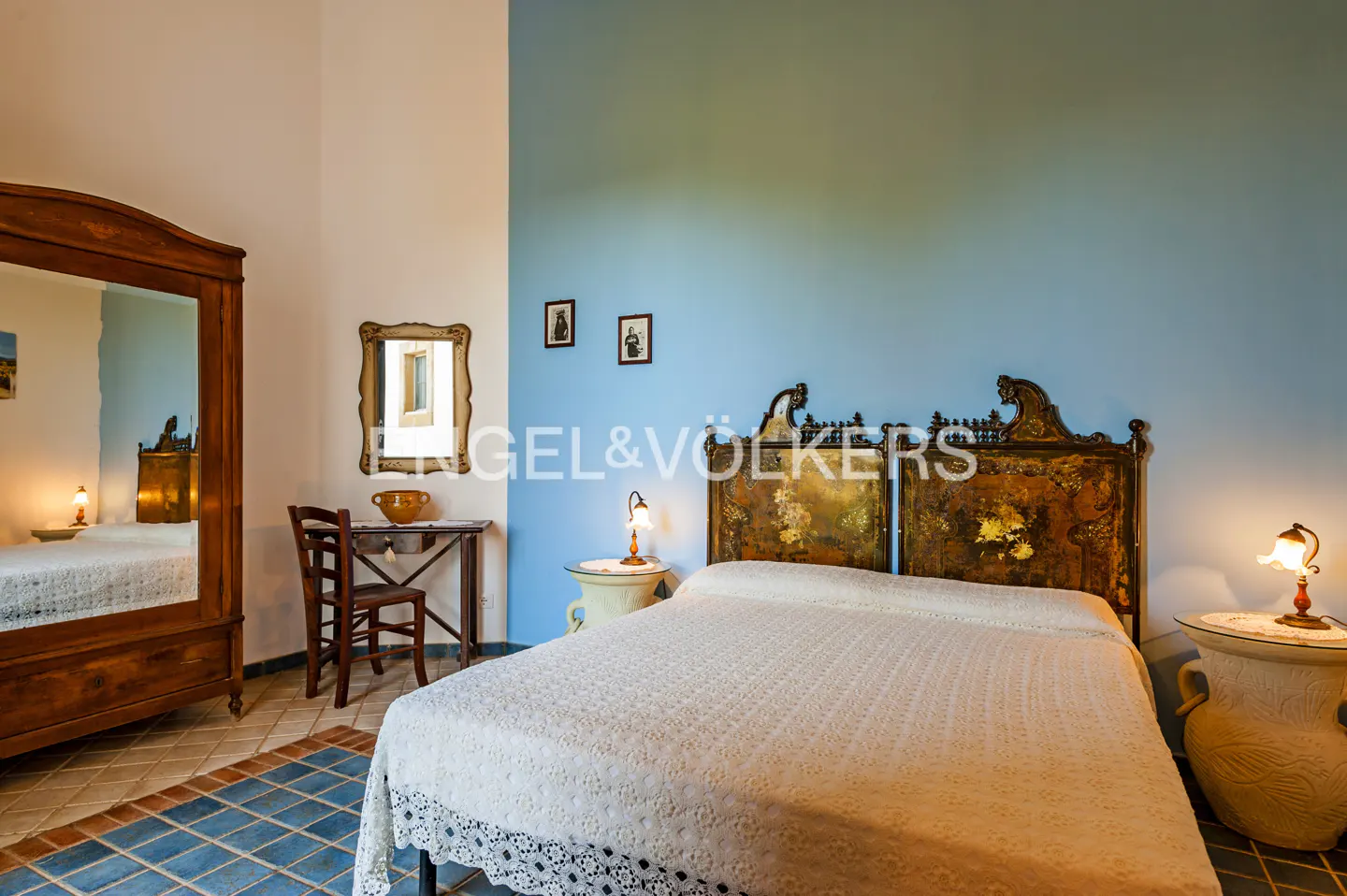Bedroom with a blue wall, a bed with a white cover, a wooden headboard, and a wooden wardrobe.