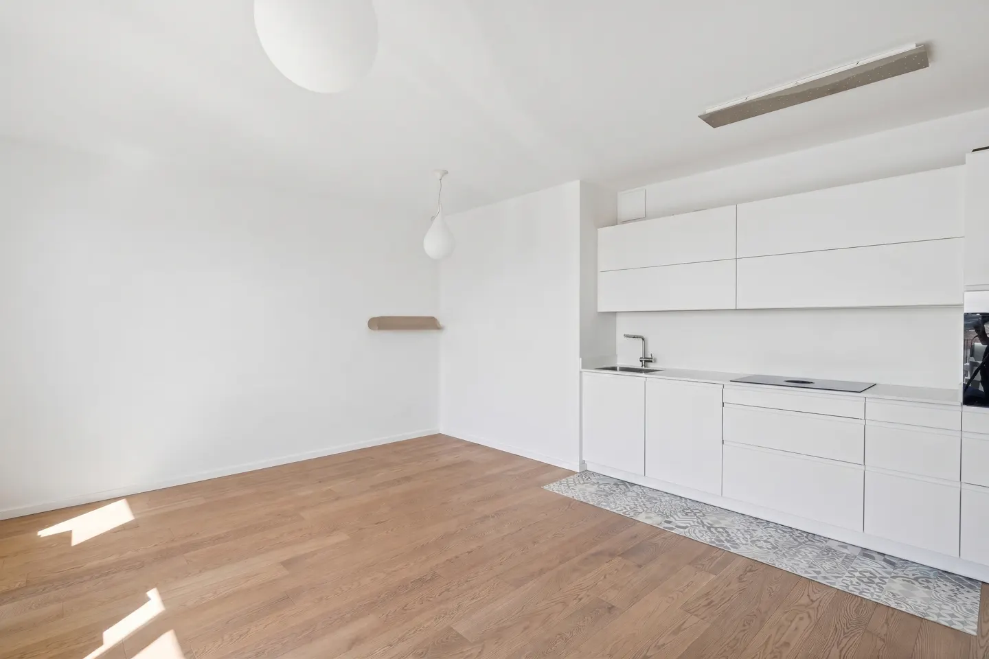 Bright, modern kitchen with white cabinets, wood floors, and a patterned rug. A minimalist design with a clean, open space.