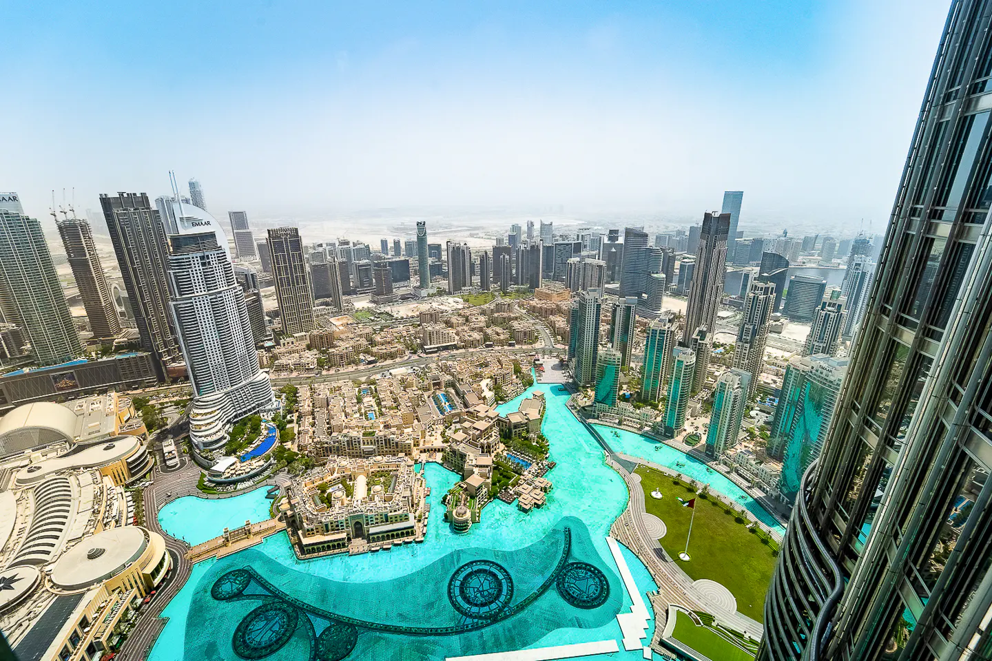 Aerial view of Dubai, featuring turquoise water, skyscrapers, and the Burj Khalifa.