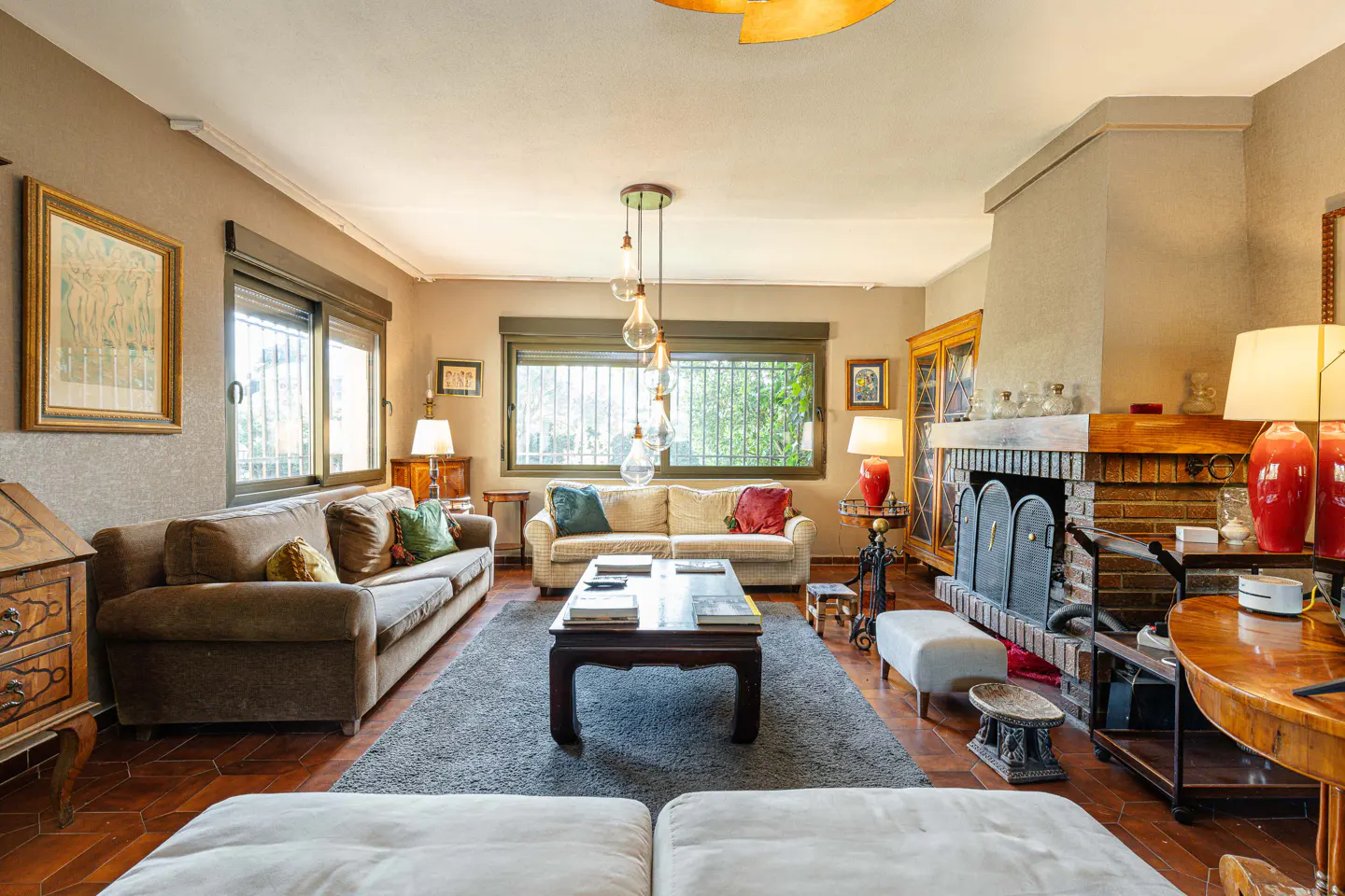 A living room with two sofas, a coffee table, a fireplace, and a gray rug on a terracotta floor.