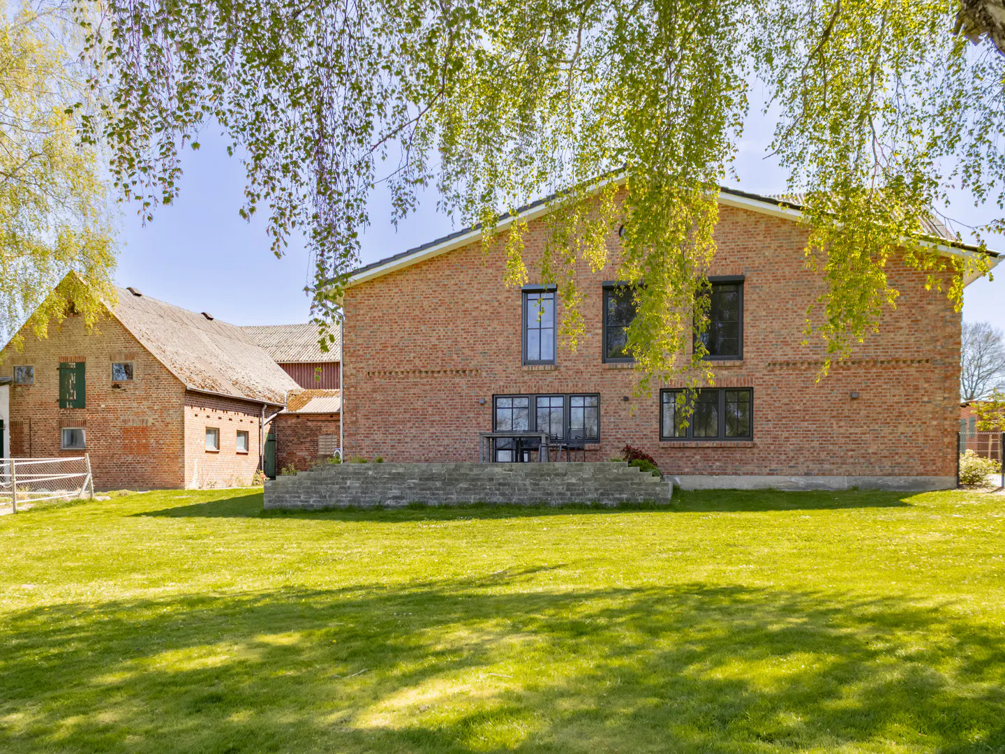 Exterior view of a red brick house with a green lawn and trees.