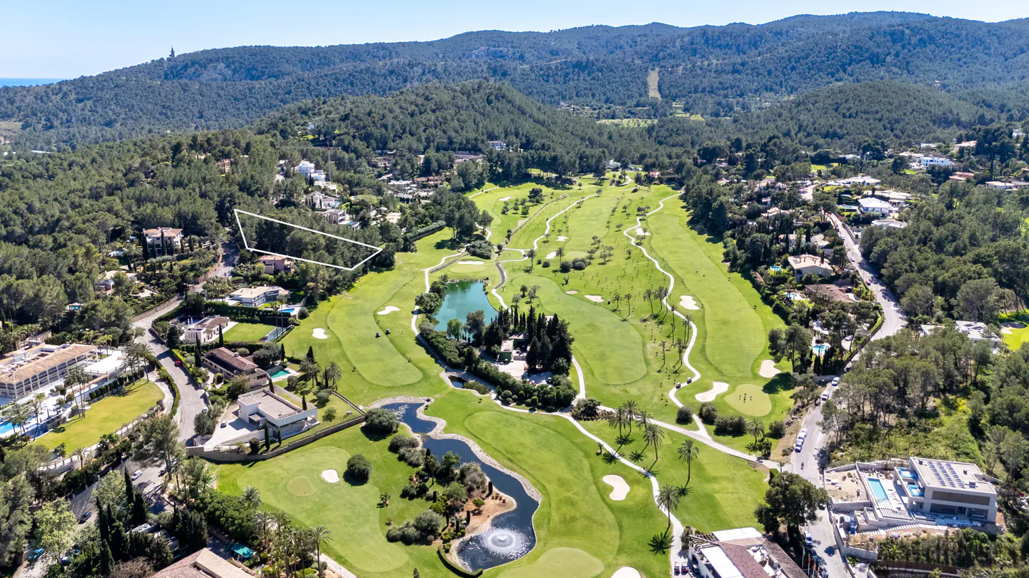 Aerial view of a green golf course with ponds, trees, and houses, surrounded by mountains and a white outlined property.