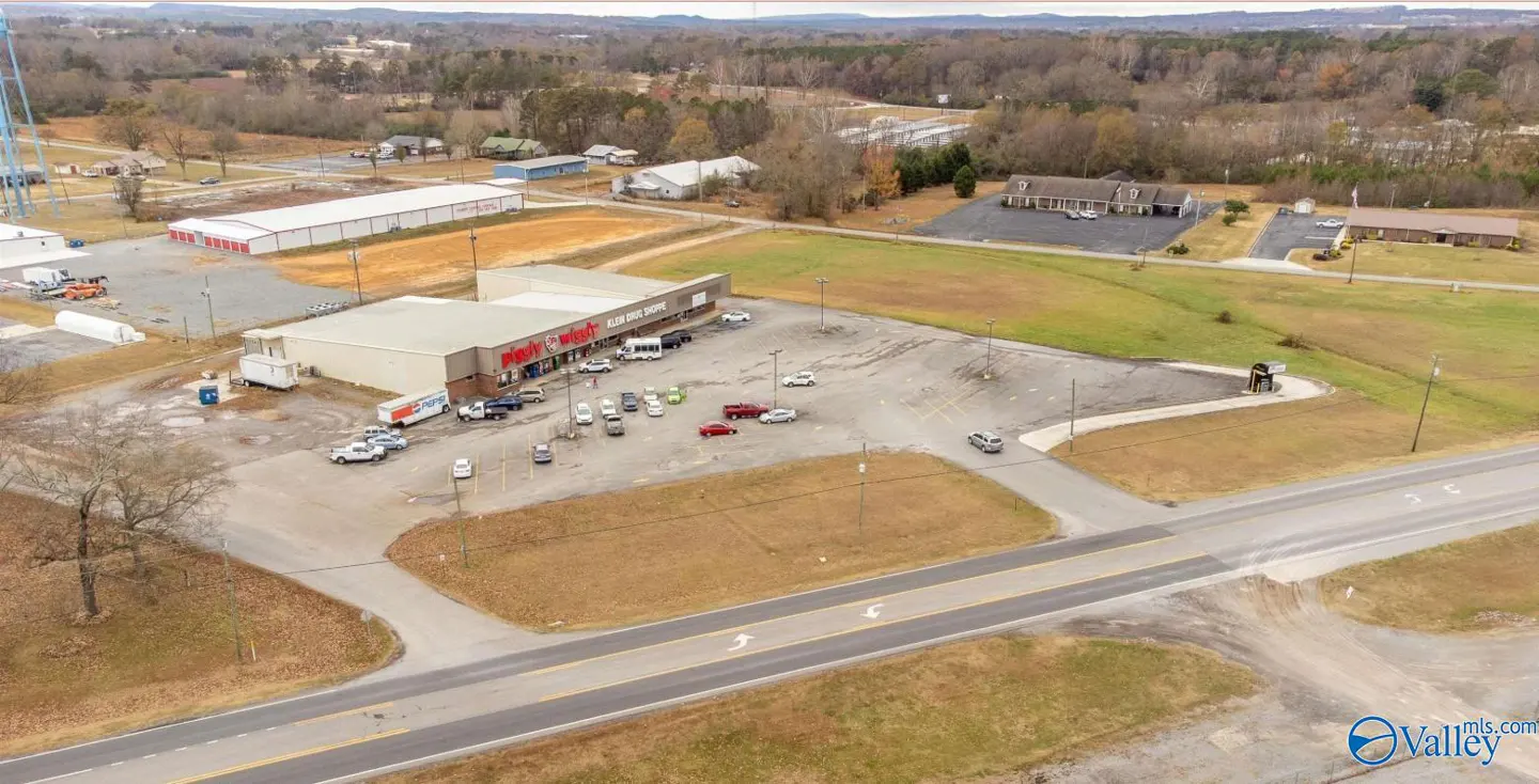 Aerial view of a commercial property featuring a large parking lot, retail building, and surrounding landscape.
