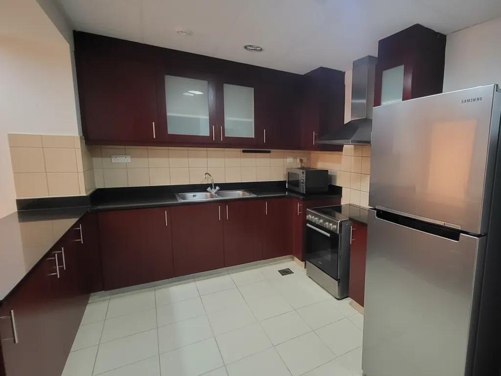 A kitchen with dark wood cabinets, stainless steel appliances, and a light tile floor.