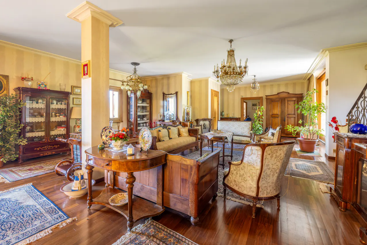 A spacious living room with hardwood floors, antique furniture, and crystal chandeliers.