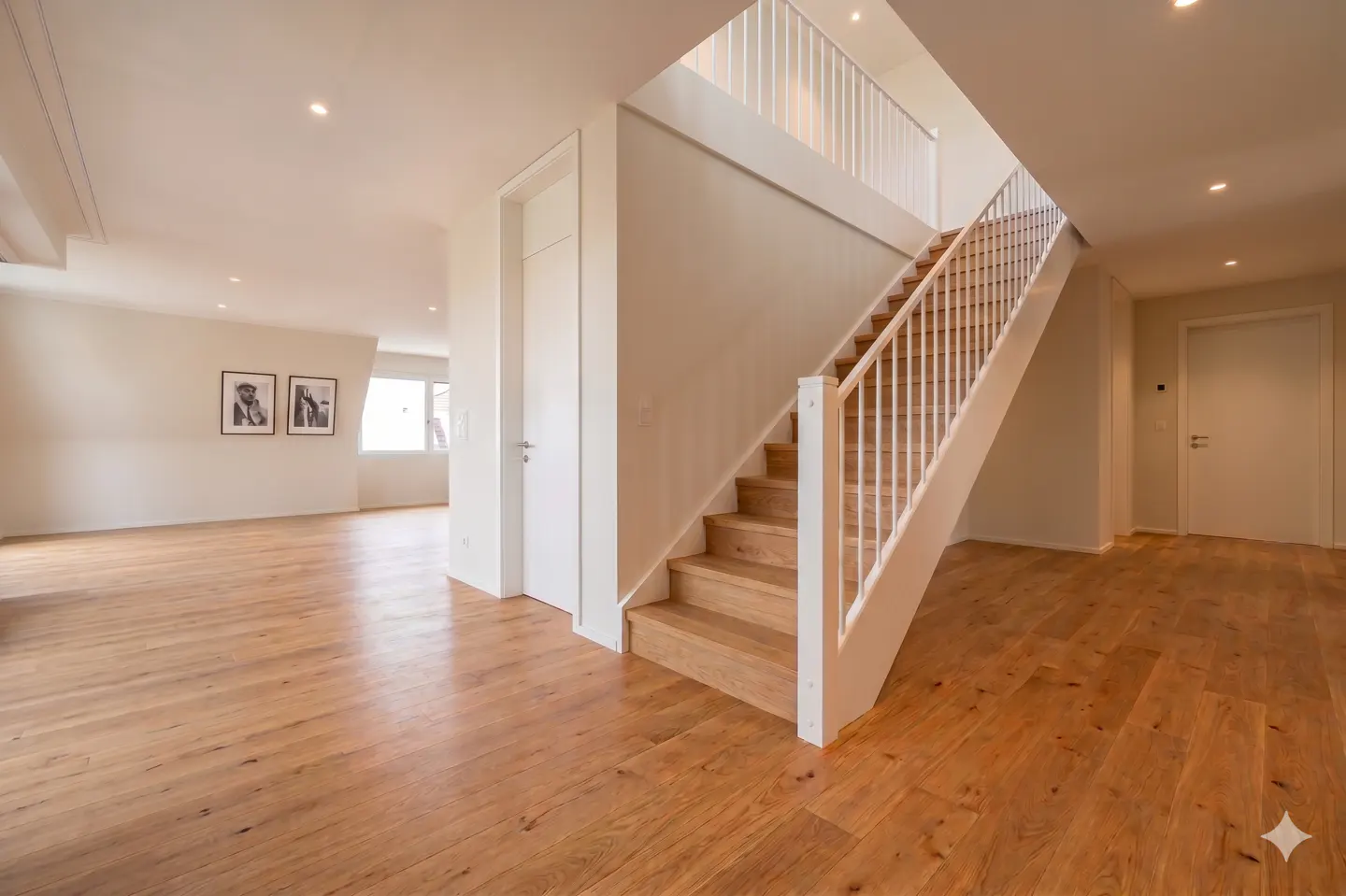 Bright, modern home interior with light wood floors, white walls, and a staircase with white railings leading to the second floor.