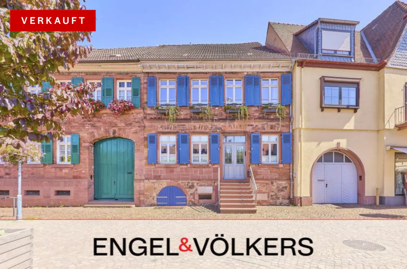 Exterior of a three-story building with blue shutters and a "Verkauft" sign.